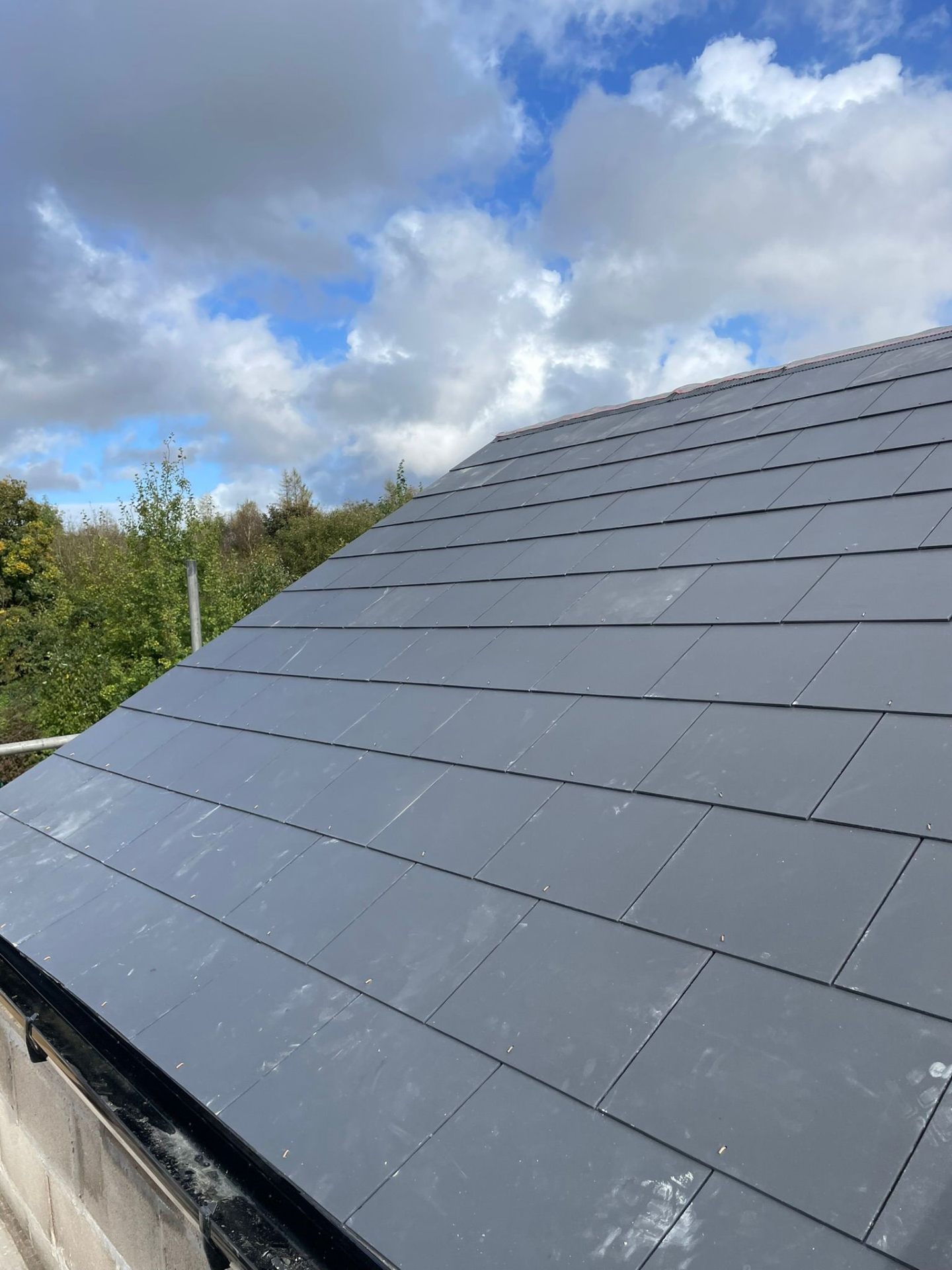 Close-up of newly installed dark slate roof tiles on a pitched roof in South Wales